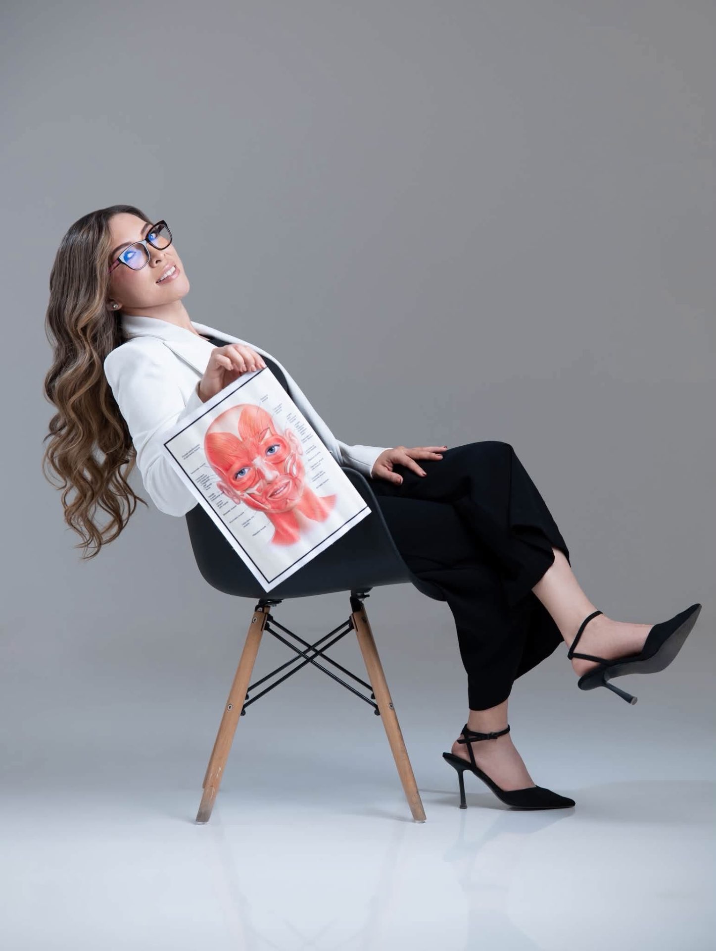 Dra. Doris Mendoza sentada con lámina de músculos faciales